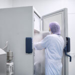scientist standing with freezer door open