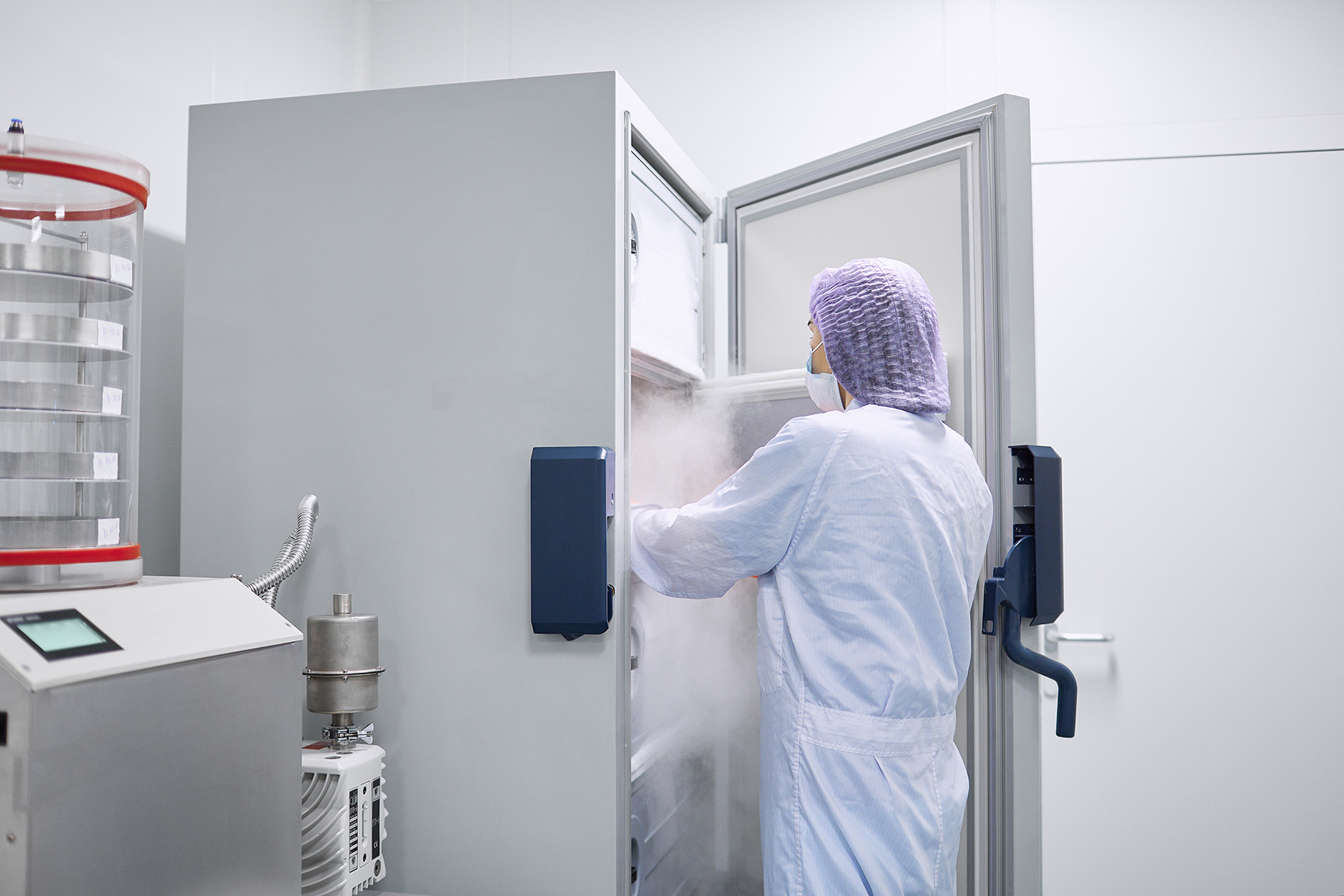 scientist standing with freezer door open